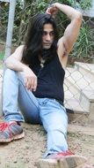 a man with long hair is sitting on the ground