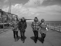 black and white photo of girls walking along the promenade