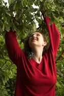 girl in a red sweater near a green tree