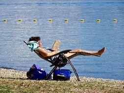 woman is resting on a beach chair by the lake