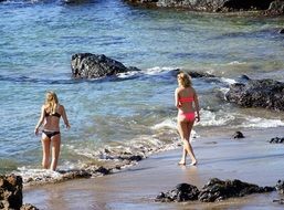 two Young Women in Bikini on beach walking to water, back view