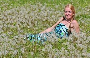 blonde in a green dress on a dandelion field