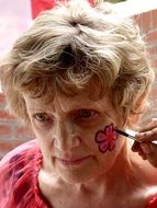 old woman with a bright flower on her cheek