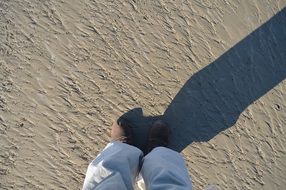 legs of a young woman in shoes on the sand