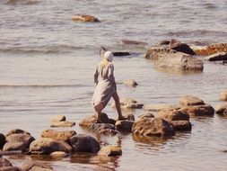 girl in a vintage dress walks on the stones on the coast, Sweden
