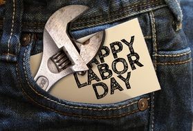 Happy labor day sign on a paper and wrench in a pocket