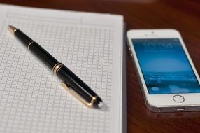 notebook, pen, smart phone on computer desk