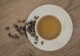 cup of coffee on a plate with coffee beans
