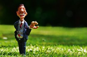 figurine of a happy businessman on green grass