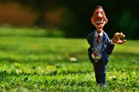 happy businessman figurine on green grass