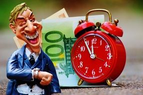 alarm clock, figurine of businessman and banknotes
