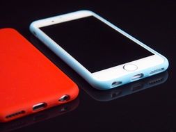 red and ehite smartphones on the black surface