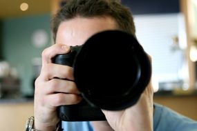 man taking pictures with a black camera with a big lens