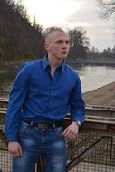 Photo of a young man in jeans on a bridge