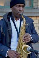Busking African man plays saxophone on street