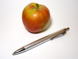 red Apple and metal Pen at white background