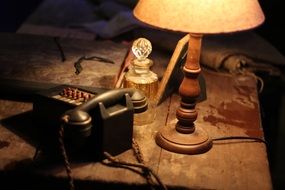 vintage table lantern, stationery phone and bottle on dirty wooden table