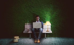 man works with laptop on a bench in a soft room