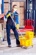 Working girl in uniform with a mop in hands