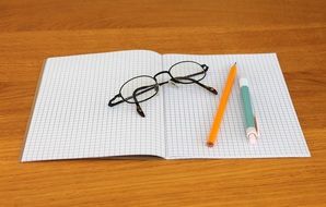 Glasses and pencils lie on the notebook