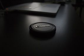 black lens cap canon on the table