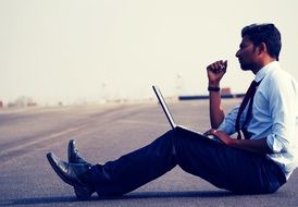 man sits on the ground with laptop