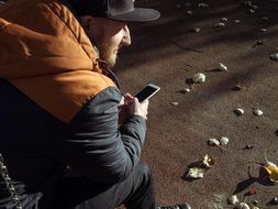 man sitting in a park with Iphone 6S Plus