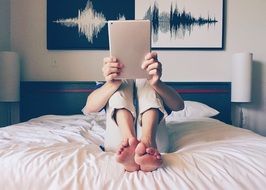 man with tablet on the bed