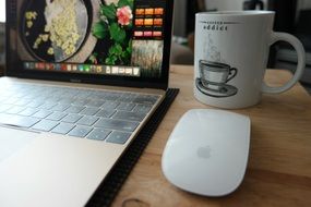 laptop, white mouse and a cup of coffee on the table