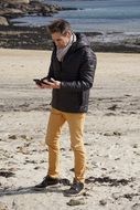 a man on the coast looking at a smartphone