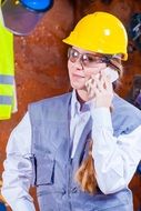 worker in a yellow helmet with a phone