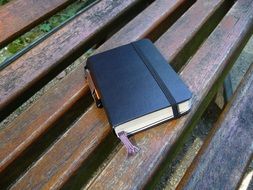 notebook lies on a wooden bench