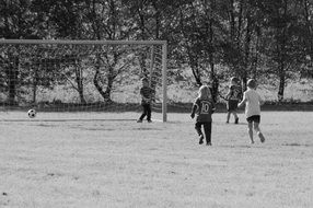 black and white photo of children playing soccer