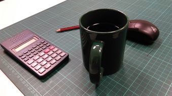 Black mug,mouse,pencil and calculator on the table