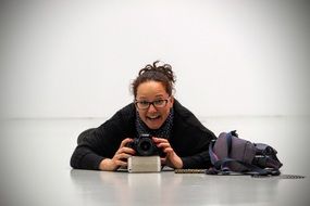 photographer, happy woman with camera lying on floor