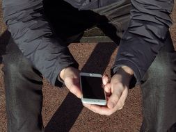 man sitting outdoor with Iphone 6S Plus