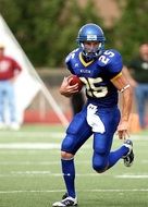 american football player in blue uniform with ball