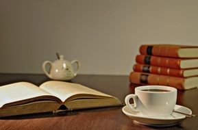 white cup with coffee and books on the table