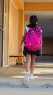 schoolgirl with a pink backpack in the school corridor