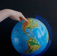 finger points to a place on the globe