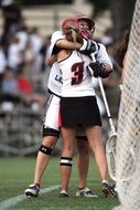 hugging uniformed Girls with sticks, Lacrosse players on field