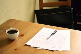 cup with coffee and documents for correction on the table