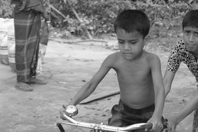 black and white photo as a boy tries to learn to ride a bicycle