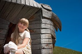 little girl sitting near a wooden building