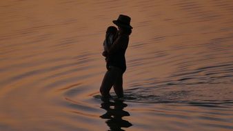 mom with a newborn in the lake at dusk