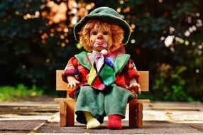 the clown doll is sitting on the bench