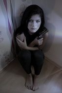 sad woman in the corner with weapon