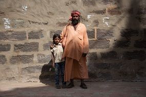 father with son near a stone building in india