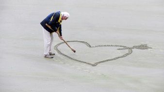 Old man drawing Heart on sand