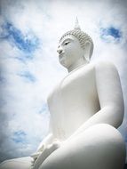 white buddha statue against the sky with white clouds